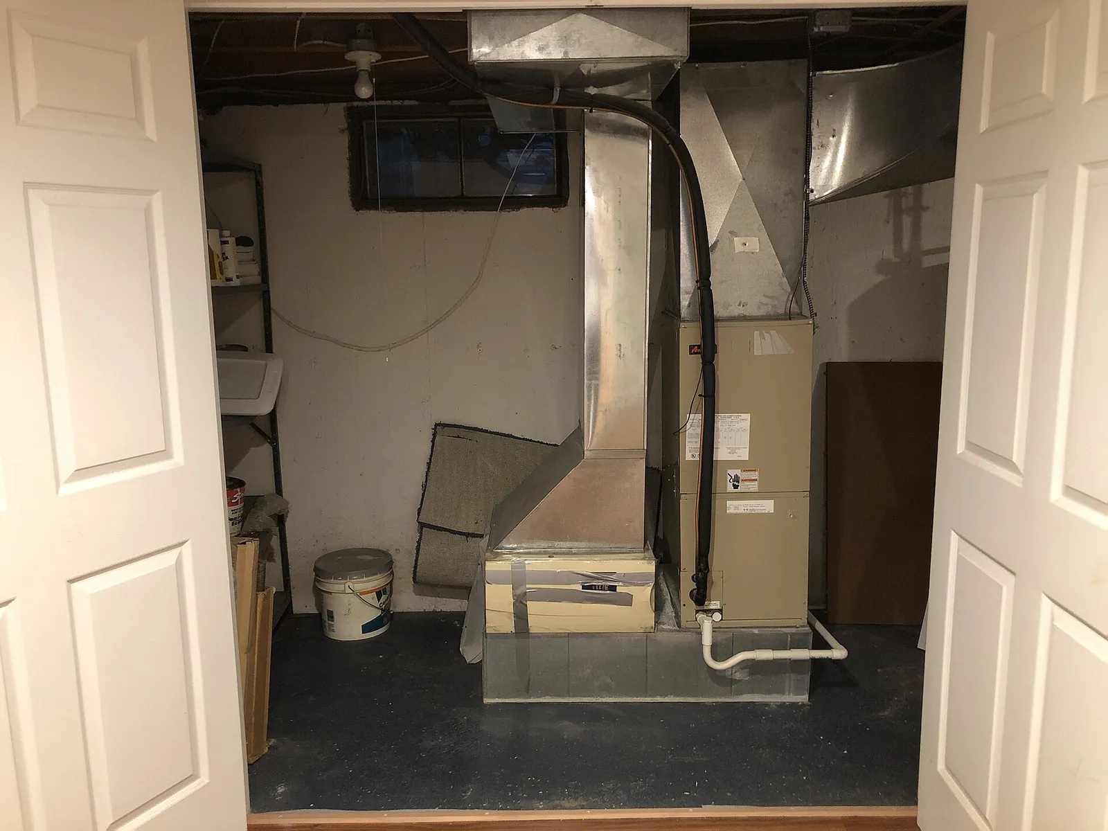 Upflow gas furnace with its supply plenum and metal ductwork in an unfinished basement utility closet